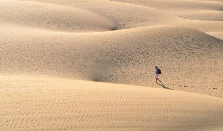 Landscape photo of a small person walking in the desert